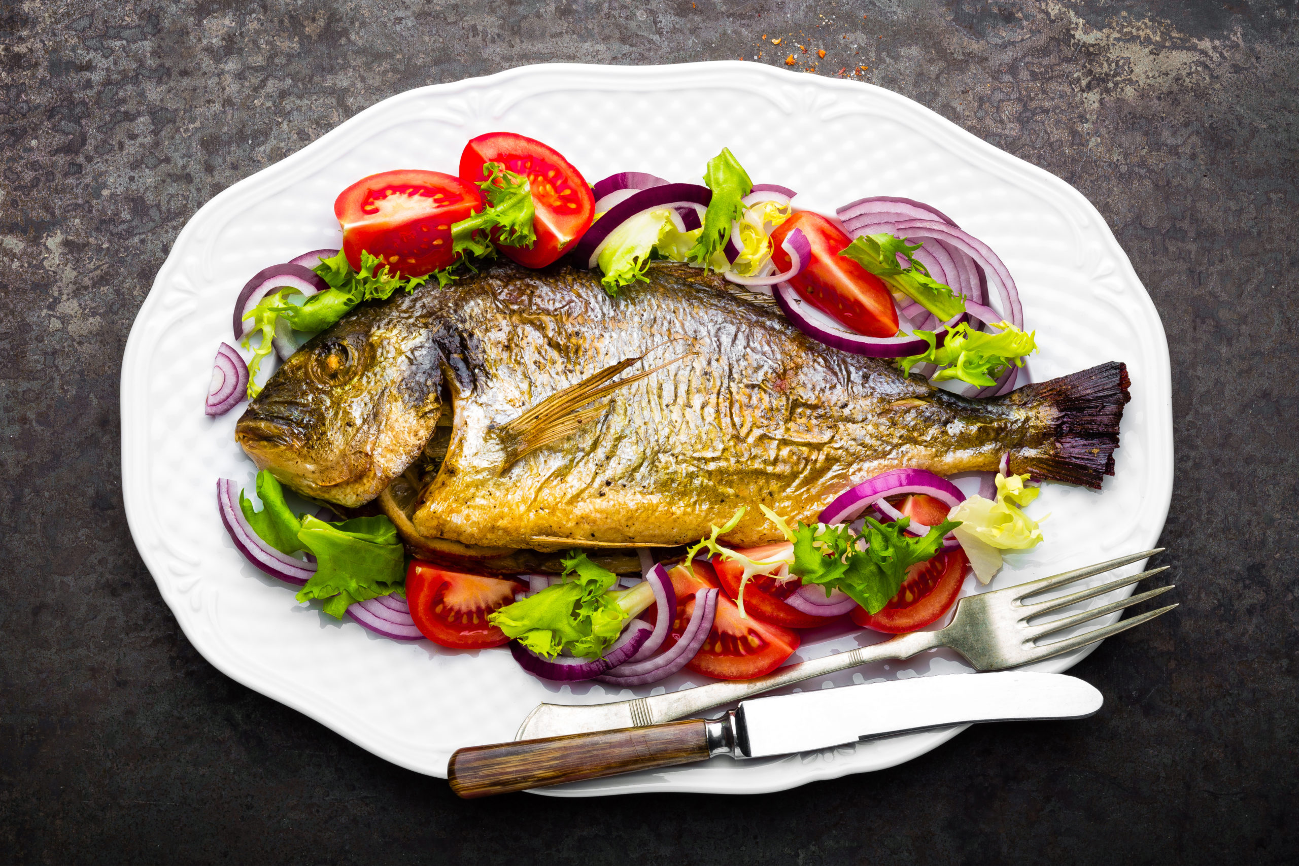 assiette de poisson cuit avec tomate, oignon et salade